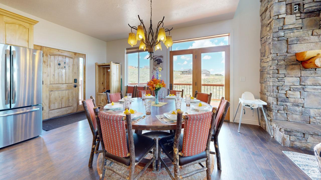 Dining room with a wealth of natural light, dark hardwood / wood-style floors, and an inviting chandelier