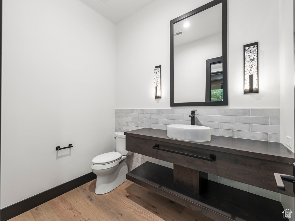 Bathroom featuring wood-type flooring, sink, toilet, and tasteful backsplash