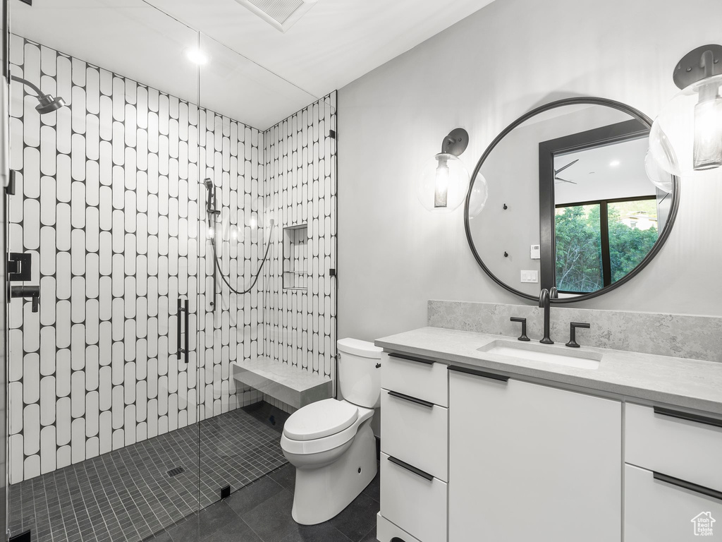 Bathroom with tile flooring, walk in shower, vanity, and toilet