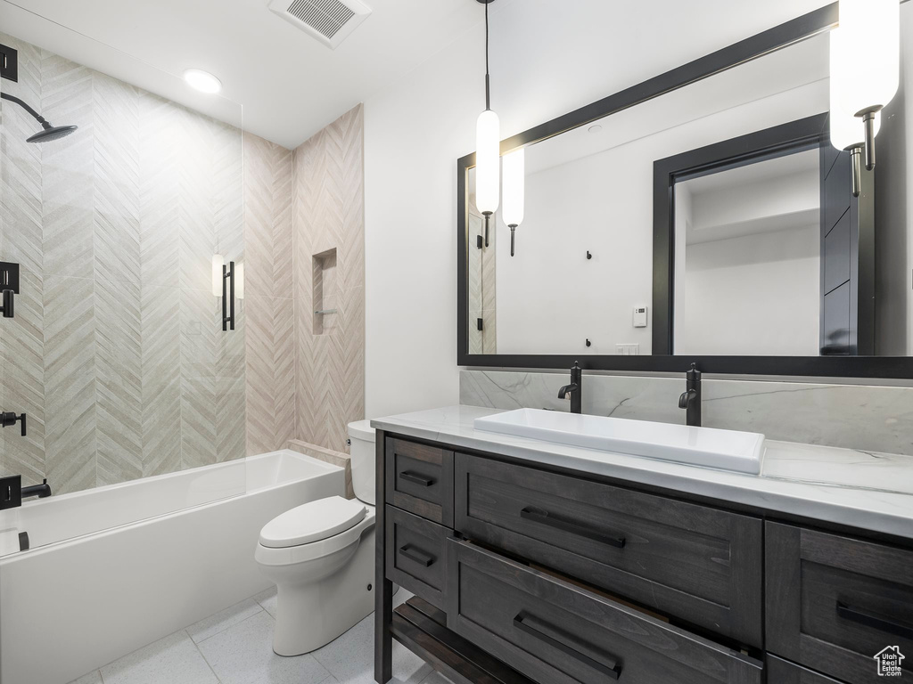 Full bathroom featuring tile floors, oversized vanity, toilet, and tiled shower / bath combo