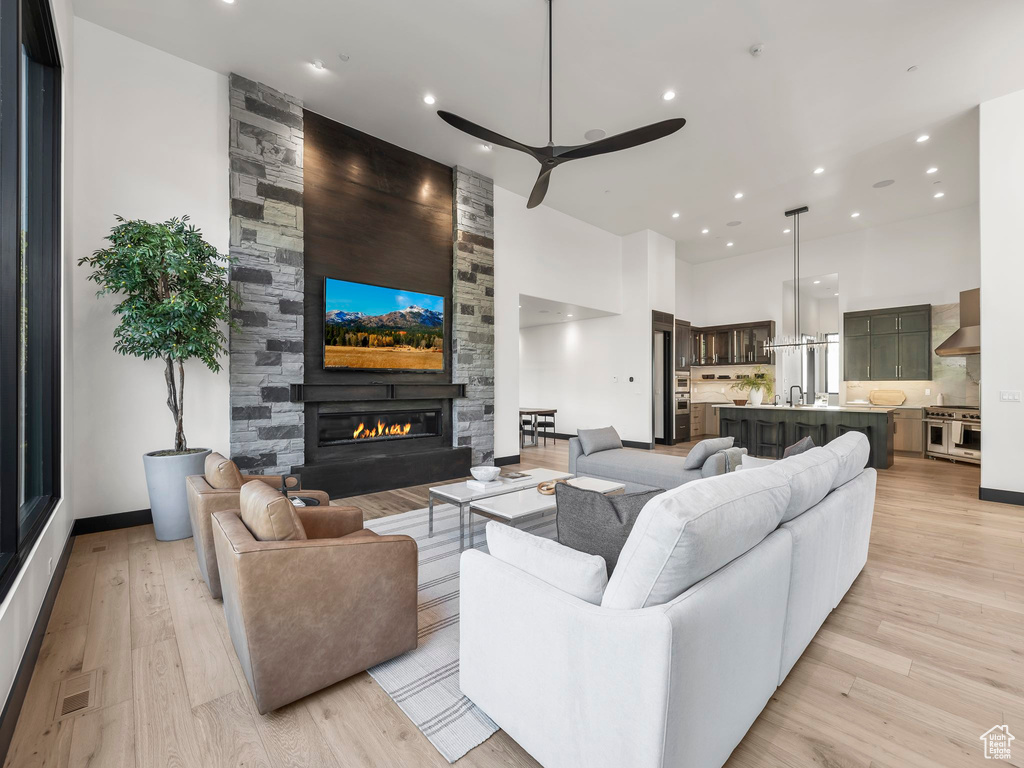 Living room with light hardwood / wood-style floors, a fireplace, a high ceiling, sink, and ceiling fan