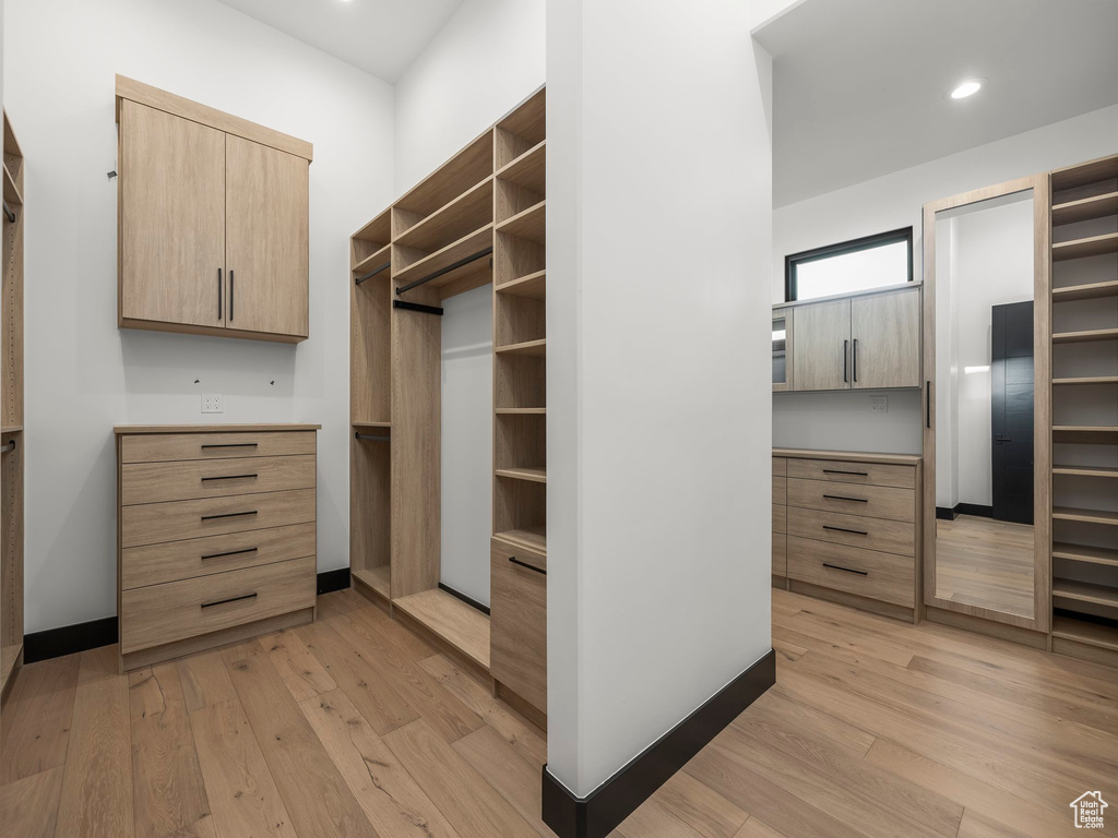 Walk in closet featuring built in desk and light hardwood / wood-style flooring