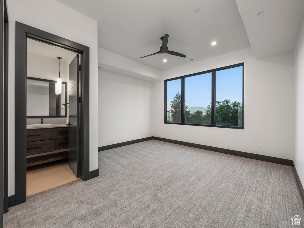 Unfurnished bedroom featuring ensuite bath, ceiling fan, light carpet, and sink