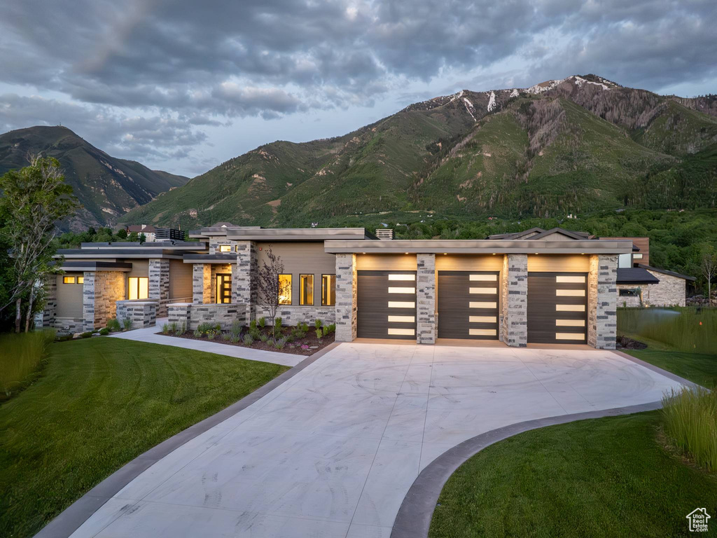 View of front facade with a garage, a mountain view, and a front lawn