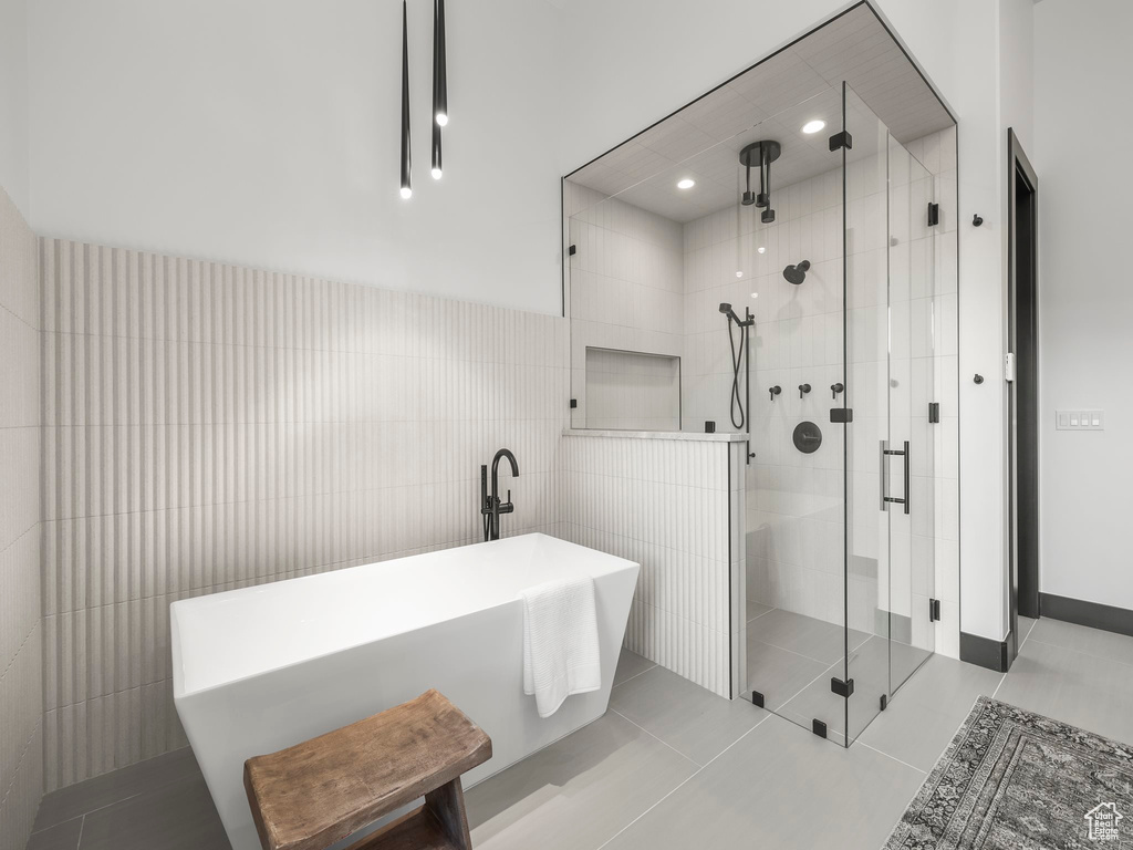 Bathroom with tile walls, tile flooring, and separate shower and tub