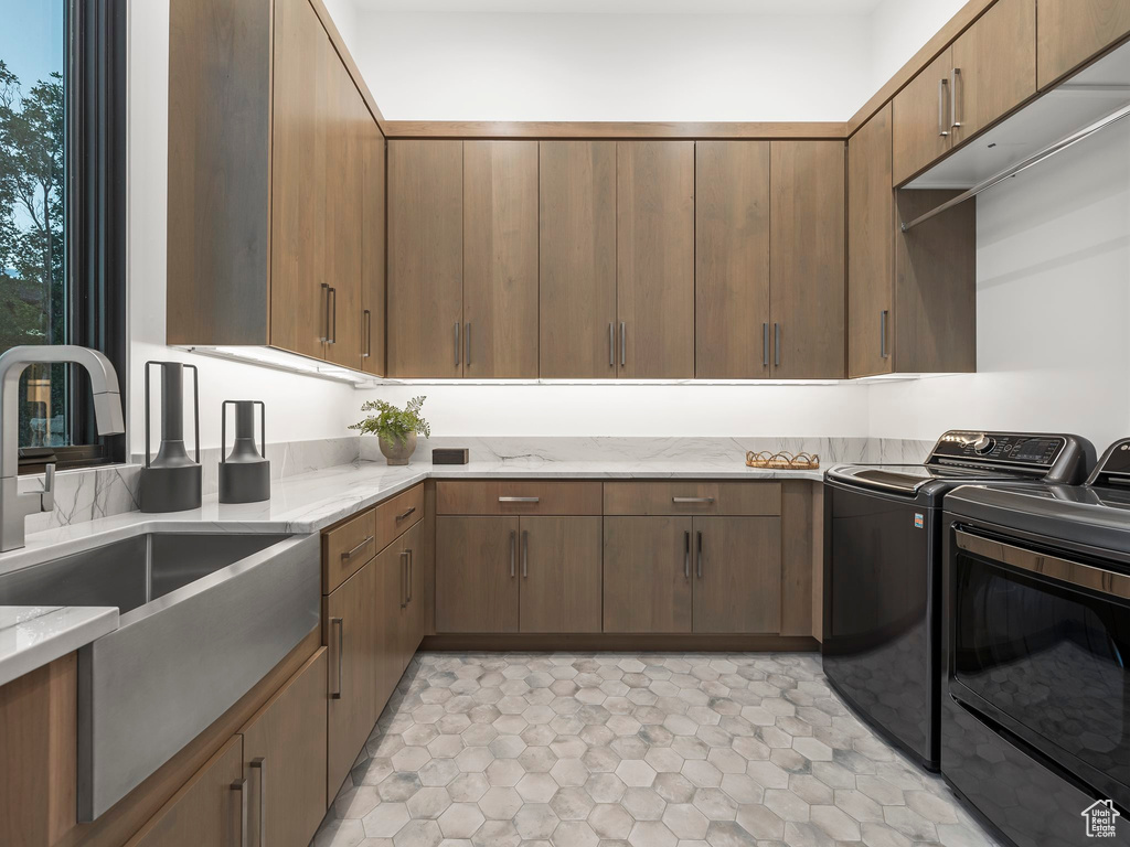 Laundry area featuring separate washer and dryer, sink, cabinets, and light tile floors