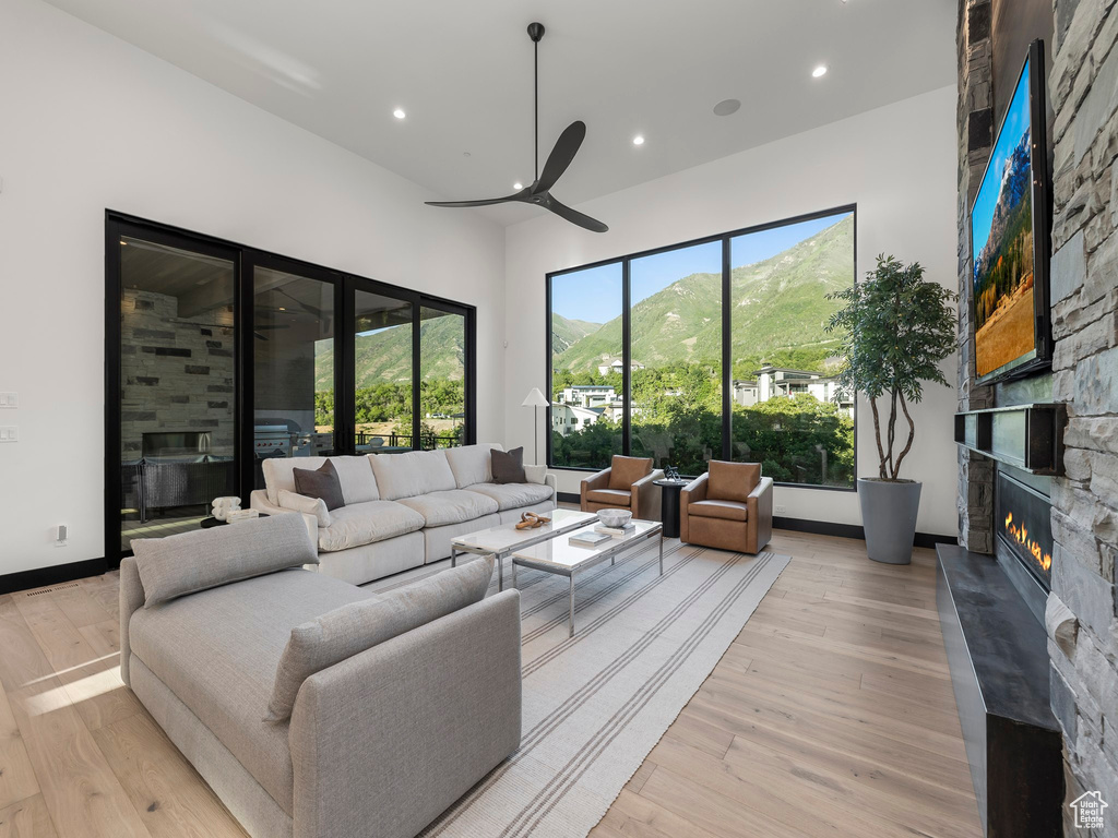 Living room with ceiling fan, a mountain view, a fireplace, and light wood-type flooring