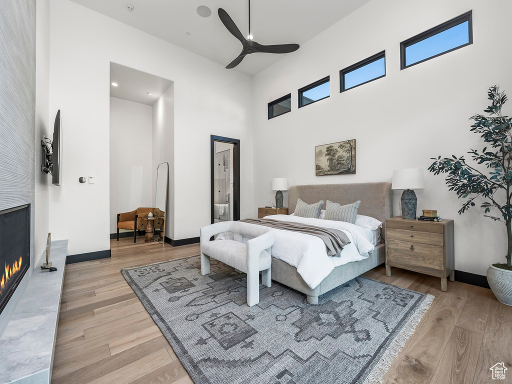 Bedroom with ceiling fan, a towering ceiling, and light wood-type flooring