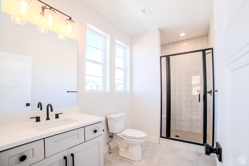 Bathroom with vanity, toilet, tile patterned floors, and a shower with shower door