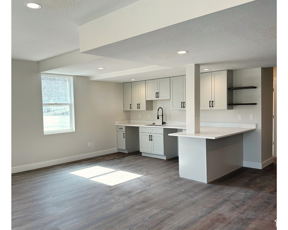 Kitchen featuring a kitchen breakfast bar, kitchen peninsula, dark hardwood / wood-style flooring, a textured ceiling, and sink