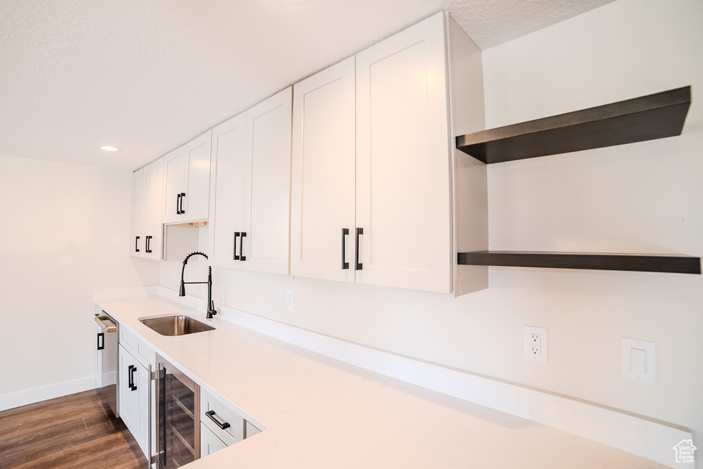 Kitchen featuring white cabinets, dark hardwood / wood-style flooring, beverage cooler, stainless steel dishwasher, and sink