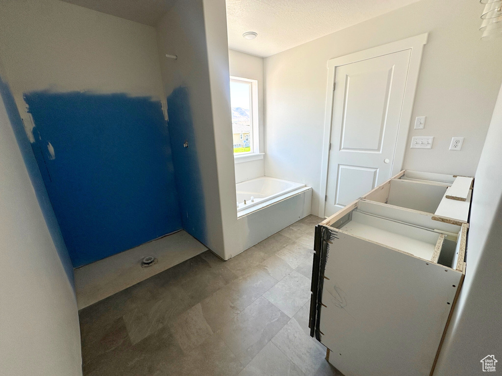 Bathroom featuring tile patterned floors, a textured ceiling, and a tub to relax in