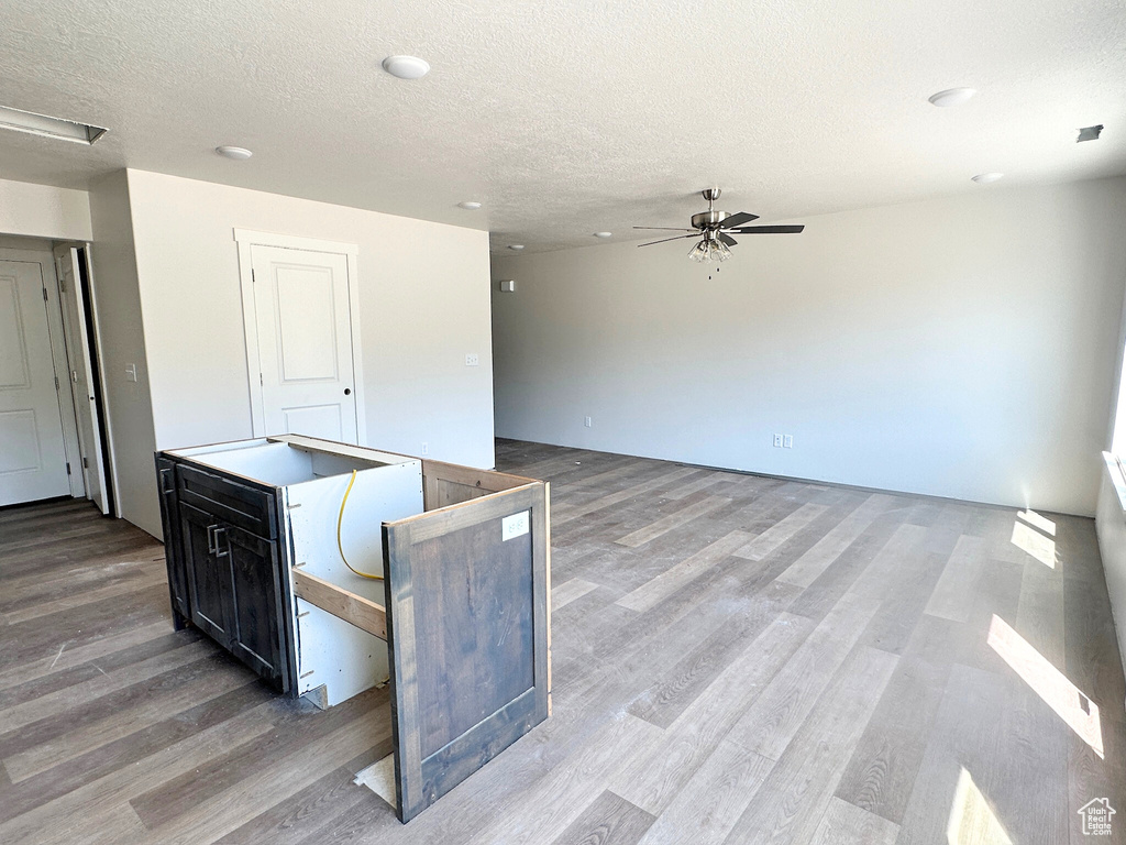 Kitchen with a kitchen island, ceiling fan, a textured ceiling, and light wood-type flooring