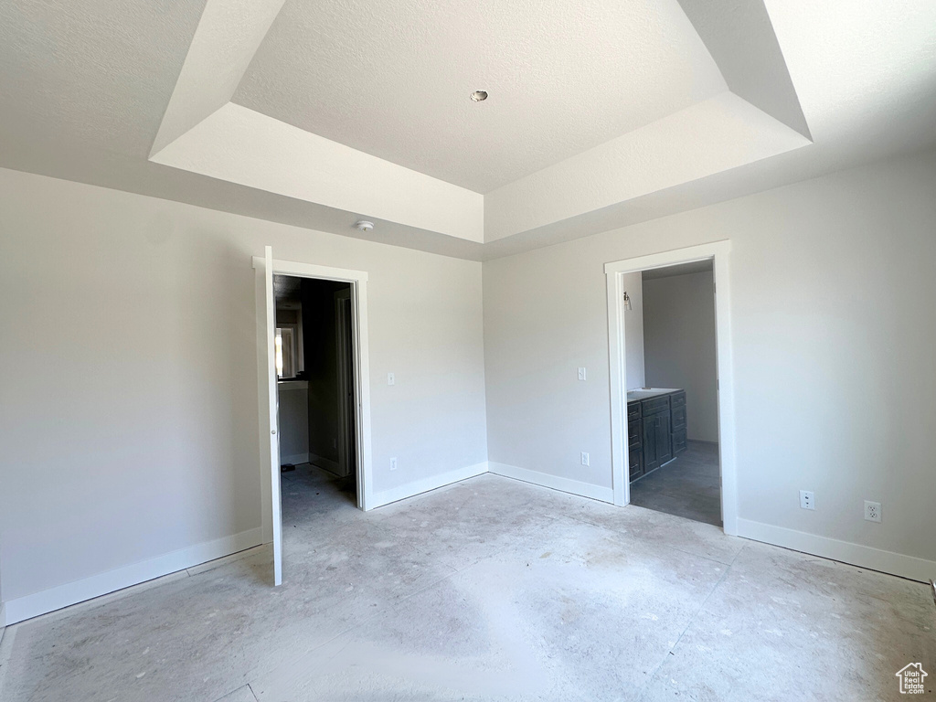 Unfurnished bedroom featuring a raised ceiling and ensuite bathroom