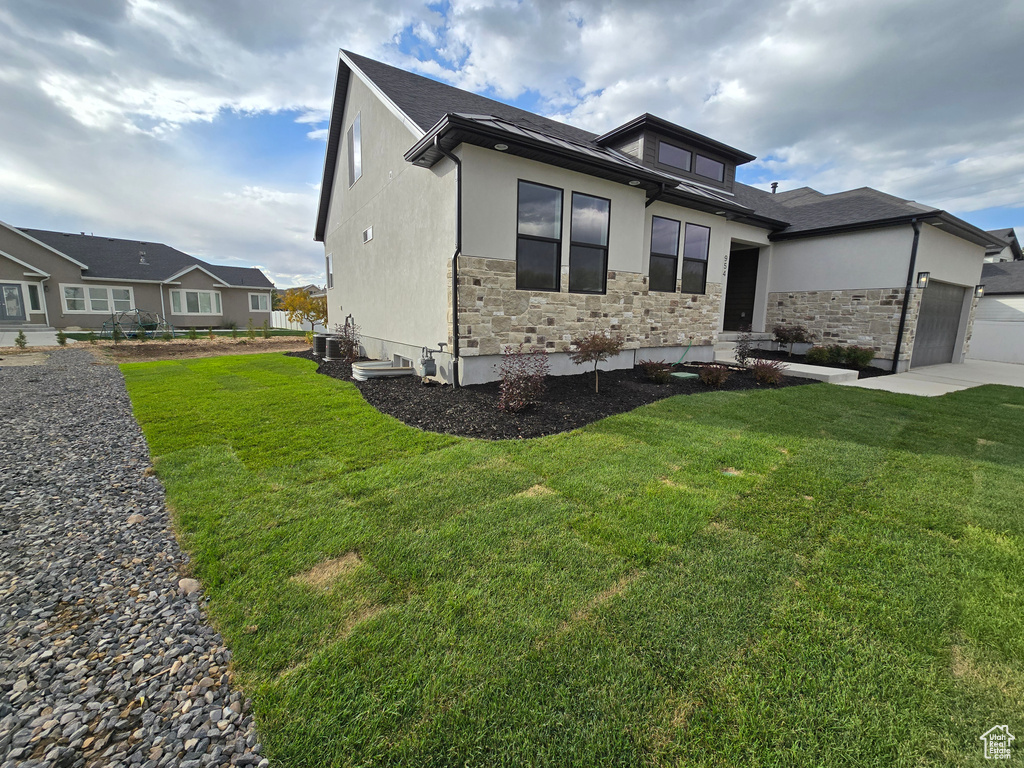 View of front facade featuring a front yard and a garage