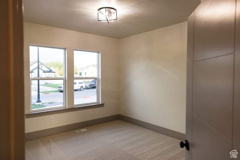 Empty room with a textured ceiling and carpet