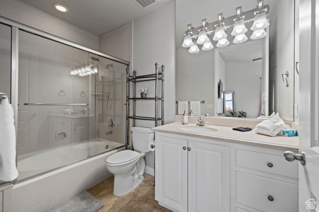 Full bathroom featuring tile floors, oversized vanity, toilet, and enclosed tub / shower combo