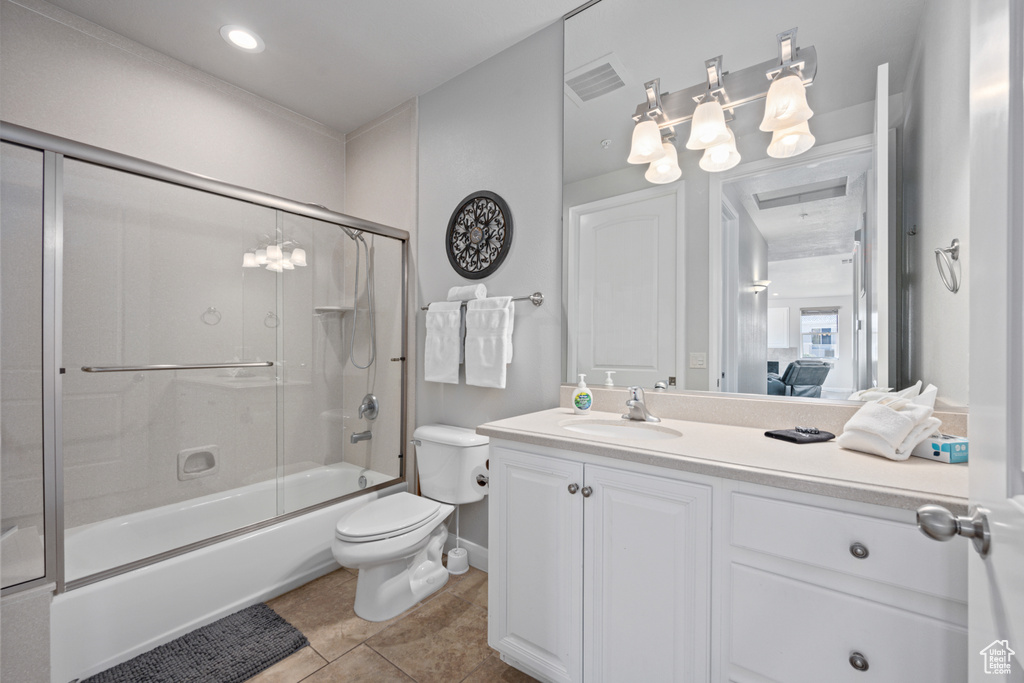 Full bathroom featuring tile flooring, shower / bath combination with glass door, oversized vanity, and toilet