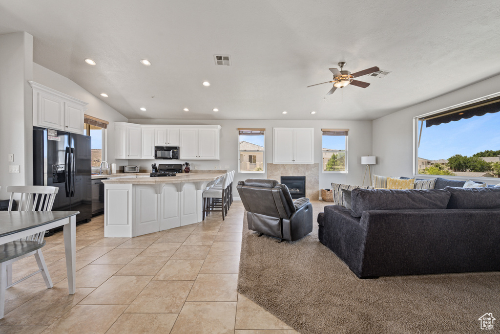 Living room with a fireplace, ceiling fan, and light tile floors