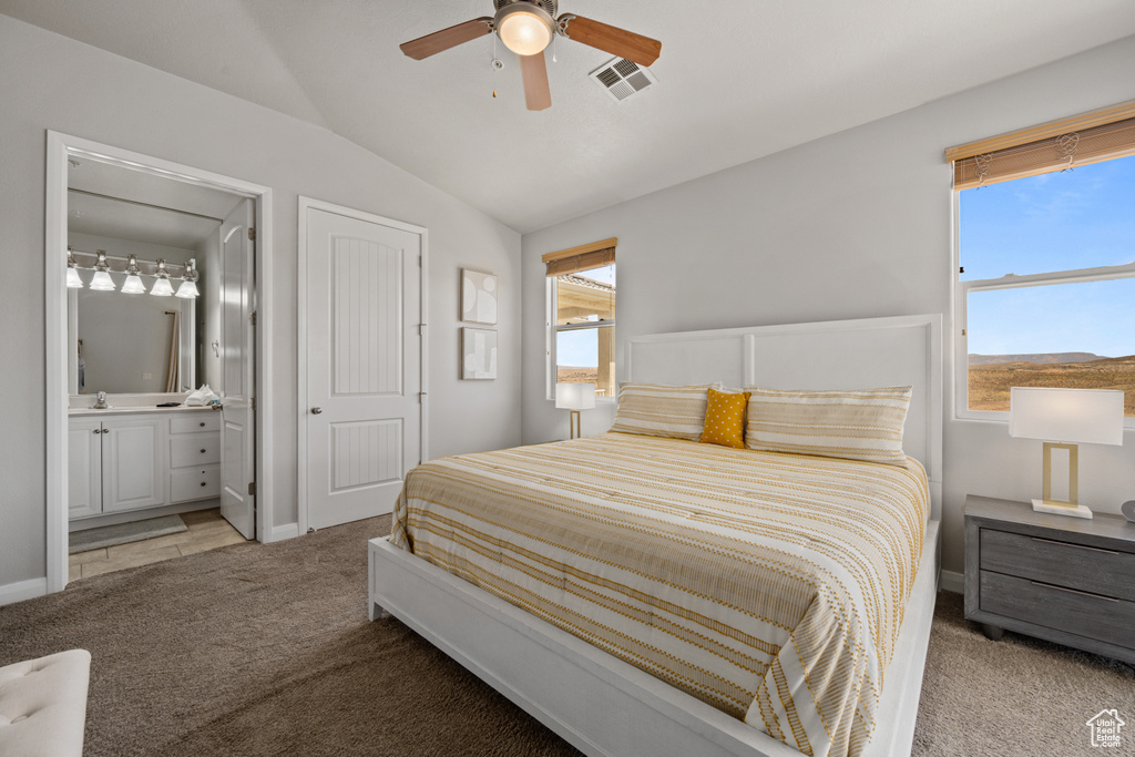 Carpeted bedroom featuring connected bathroom, lofted ceiling, multiple windows, and ceiling fan