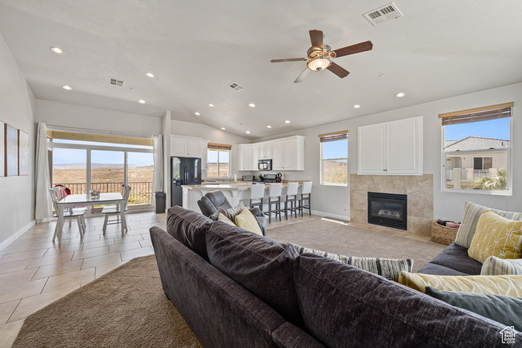 Tiled living room with lofted ceiling, plenty of natural light, ceiling fan, and a tile fireplace