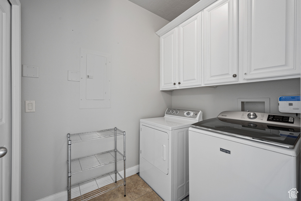 Clothes washing area featuring hookup for a washing machine, cabinets, light tile floors, and washing machine and dryer