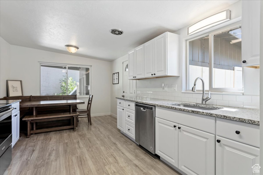 Kitchen featuring light hardwood / wood-style floors, white cabinets, sink, tasteful backsplash, and dishwasher