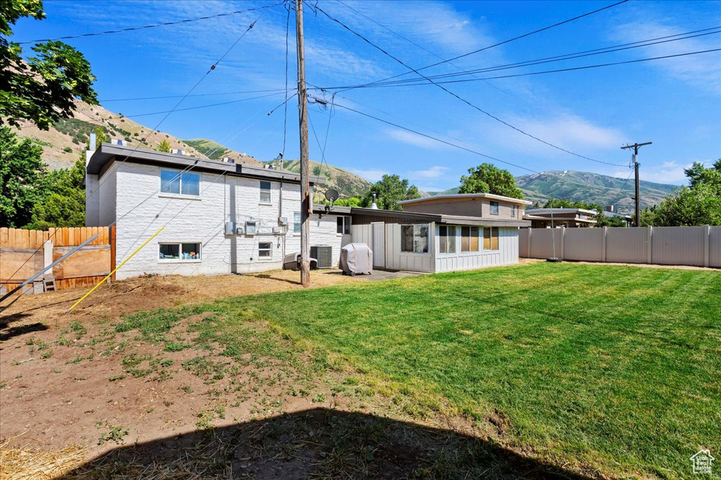 Back of house with a yard and a mountain view