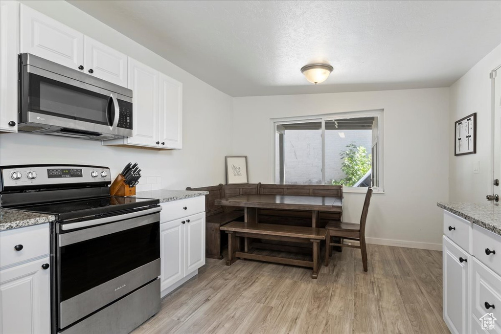 Kitchen with appliances with stainless steel finishes, white cabinetry, and light wood-type flooring