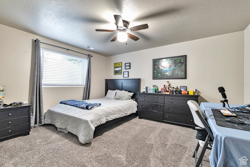 Bedroom with a textured ceiling, carpet floors, and ceiling fan