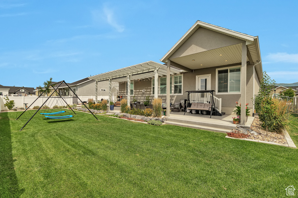 Rear view of property with a patio area, a pergola, and a lawn