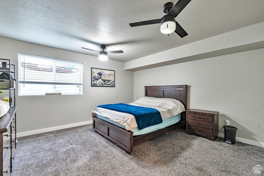 Carpeted bedroom with ceiling fan and a textured ceiling