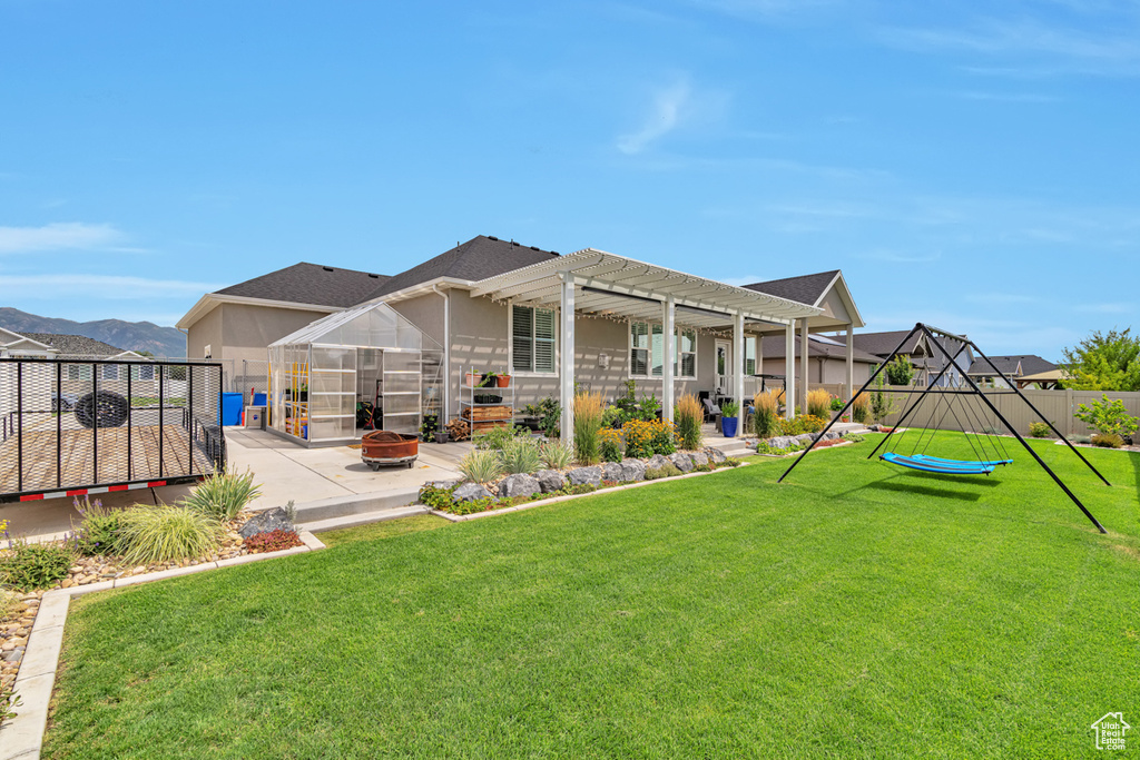 Rear view of property featuring a yard, a pergola, and a patio area