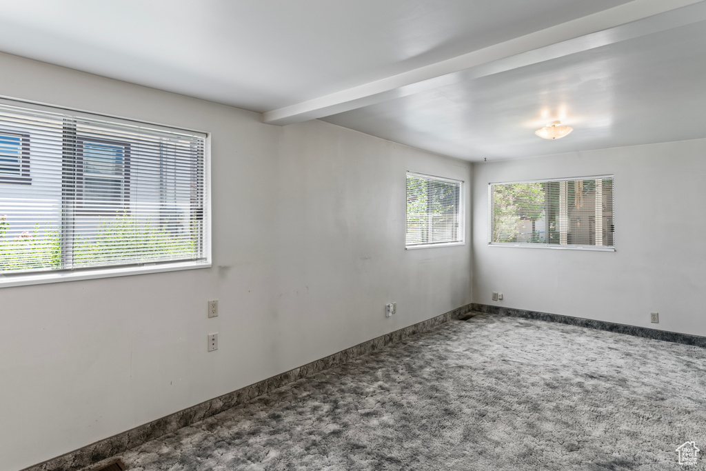 Unfurnished room with beam ceiling and carpet flooring