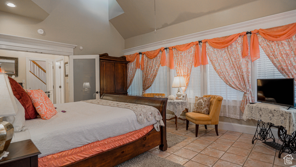 Bedroom featuring high vaulted ceiling and light tile flooring