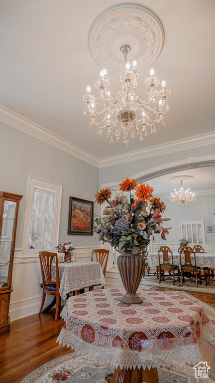 Dining room with crown molding, hardwood / wood-style floors, and a chandelier