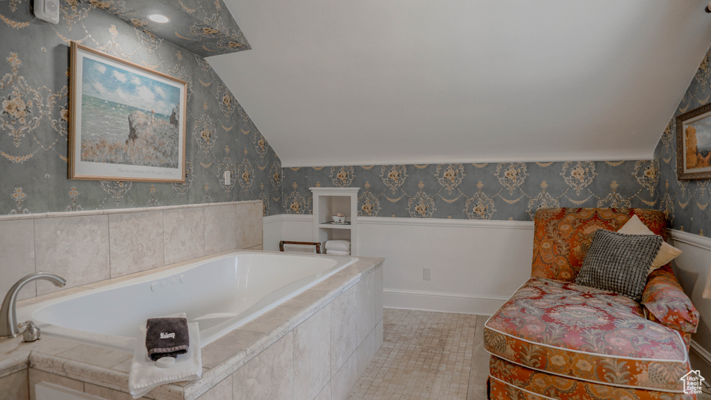 Bathroom featuring tile flooring, tiled tub, and vaulted ceiling