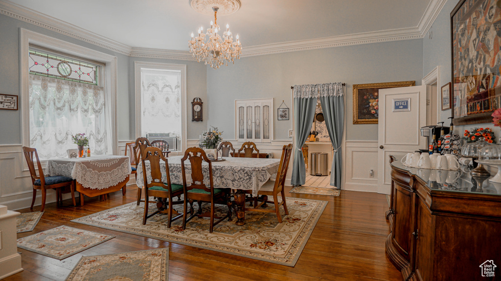 Dining space featuring ornamental molding, an inviting chandelier, and dark wood-type flooring