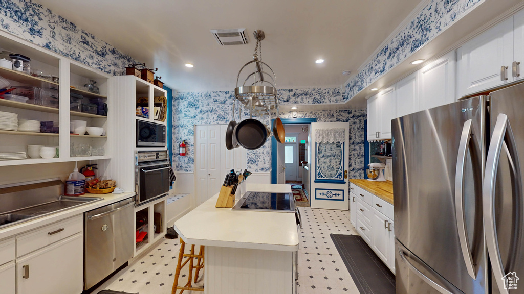 Kitchen featuring stainless steel appliances, a kitchen bar, a center island, white cabinets, and light tile floors