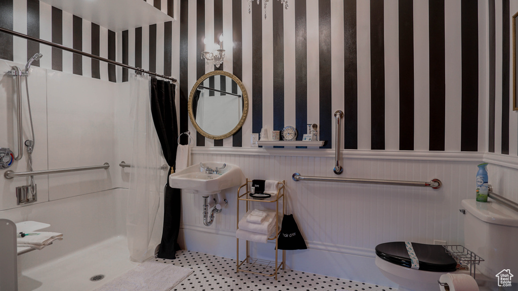 Bathroom featuring curtained shower, sink, tile floors, and toilet