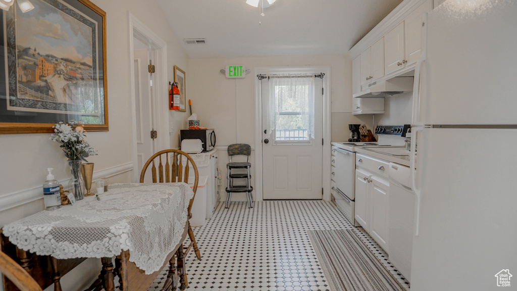 Kitchen featuring white appliances, light tile flooring, and white cabinetry