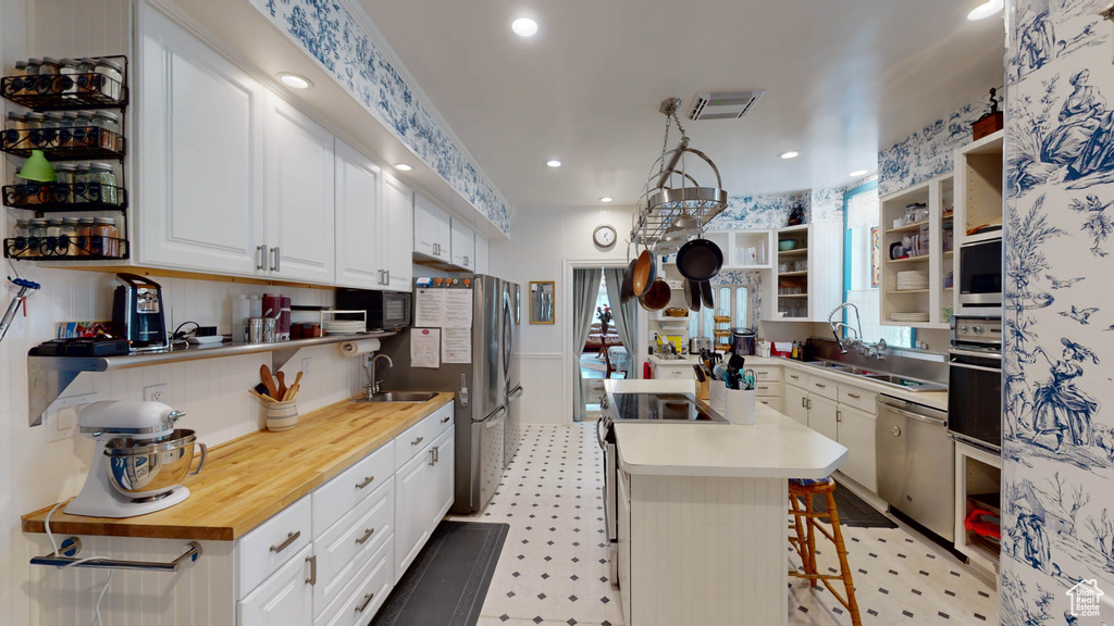 Kitchen featuring white cabinets, black appliances, light tile flooring, and a kitchen island