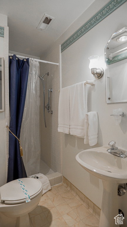 Bathroom featuring a shower with curtain, tile flooring, and toilet