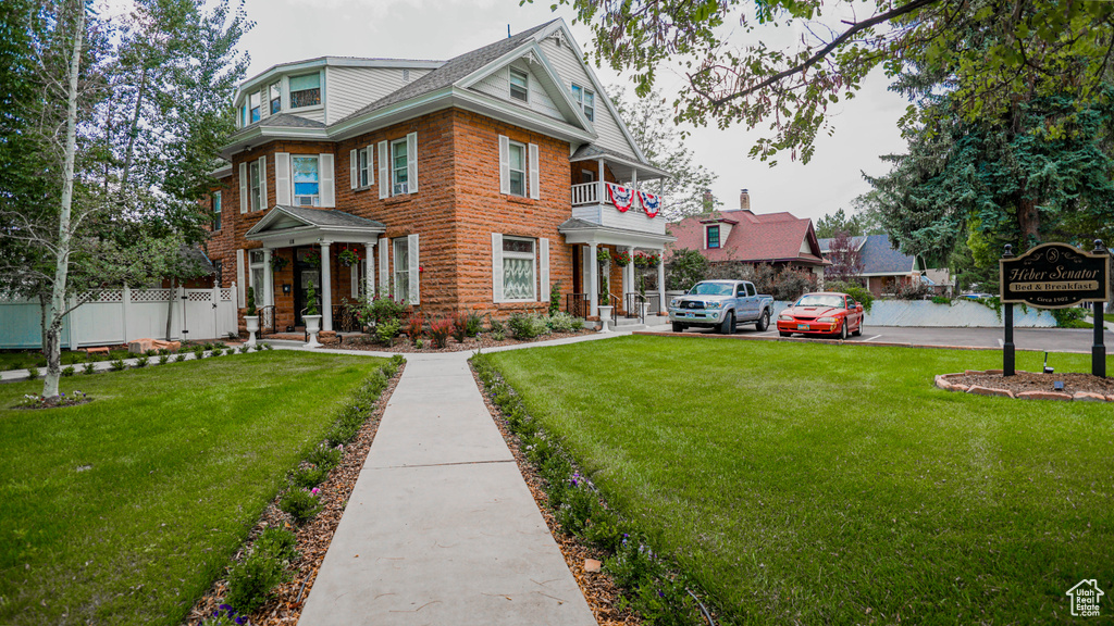 View of front of home with a front lawn and a balcony