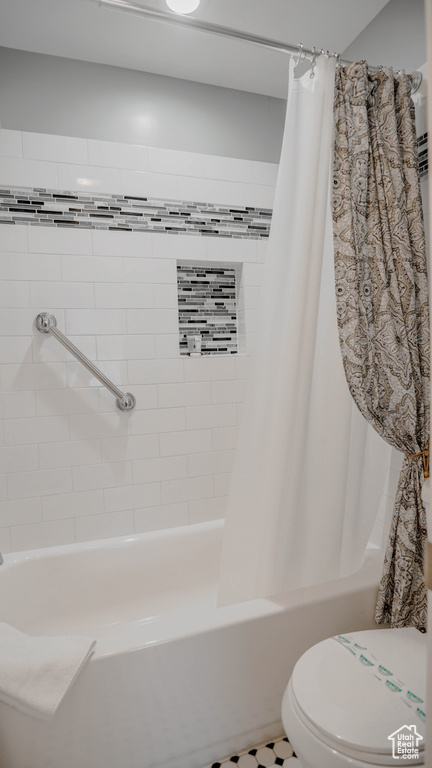 Bathroom with toilet and shower / bath combo with shower curtain