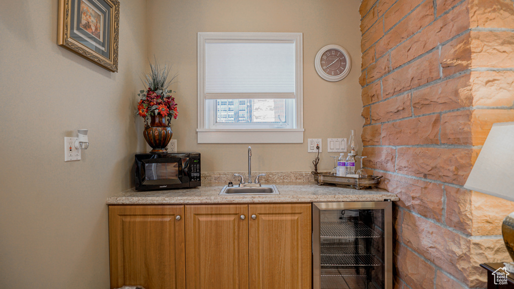 Bar featuring light stone counters, sink, and wine cooler