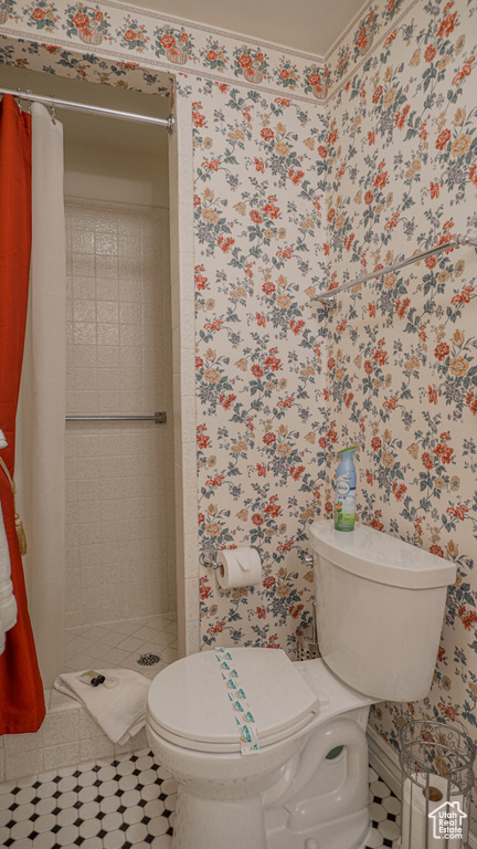 Bathroom featuring a shower with curtain, tile floors, and toilet