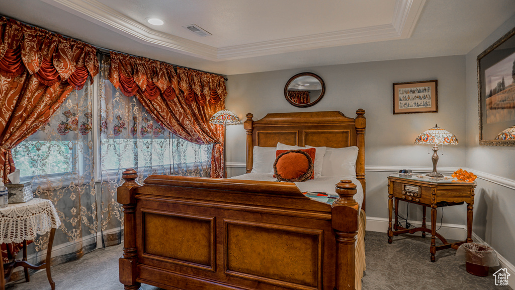 Carpeted bedroom with a raised ceiling and crown molding