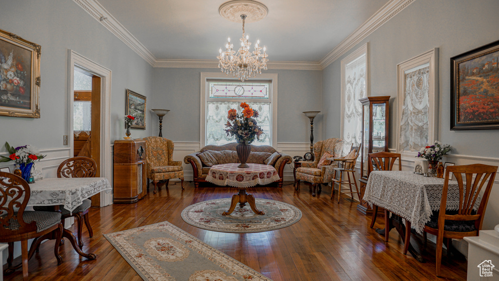 Living room with crown molding, dark wood-type flooring, and a notable chandelier