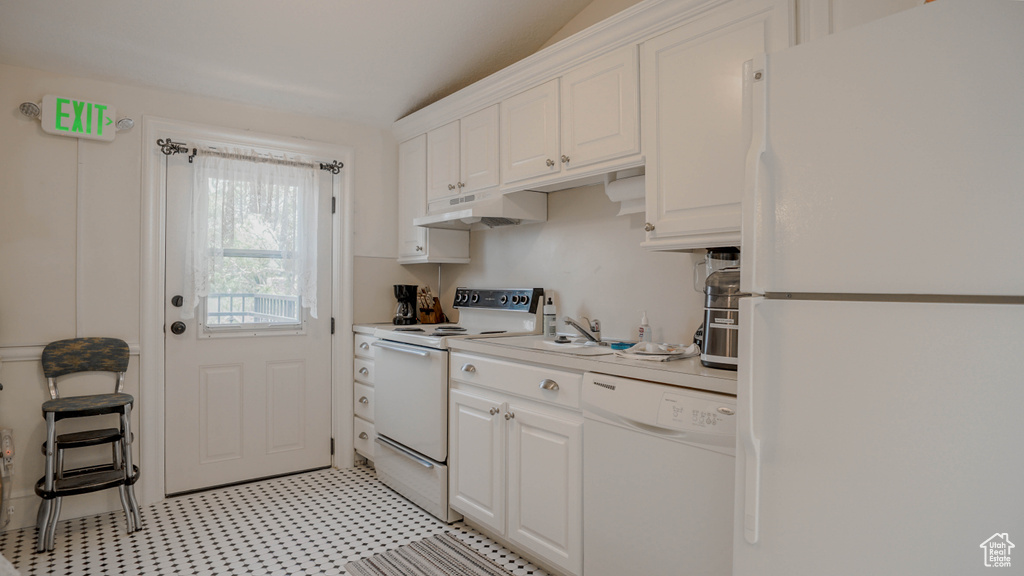 Kitchen with white cabinets, white appliances, and light tile floors